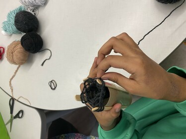 Student hands Weaving with yarn