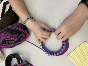 Student using a small loom to weave